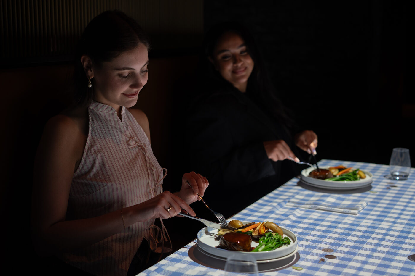 Two guests dining over the picnic-themed table projection